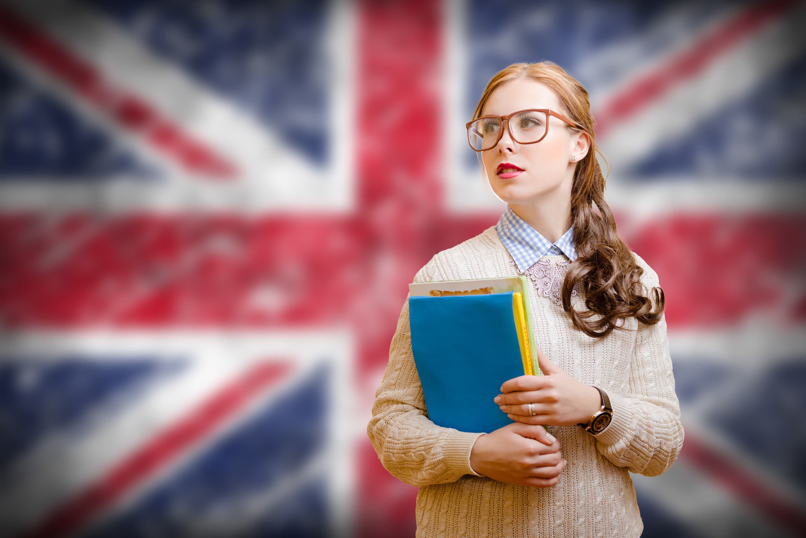 Young student standing before UK flag.